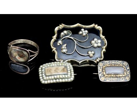 A Victorian mourning brooch, the floral spray design set with pearls on a black enamel ground within a scrolling border, the 