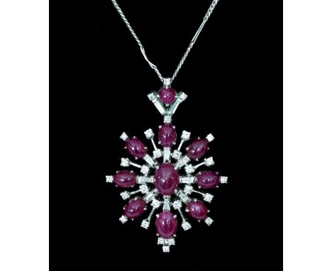 A ruby and diamond pendant of starburst form, the central oval cabochon ruby to a surround of ruby and diamond set rays, on a