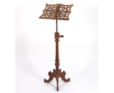 A Victorian walnut music stand with carved fretwork rest on an adjustable pole support with tripod base, the stand 50cm wide 