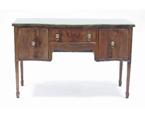 A mahogany sideboard of Sheraton design, fitted a drawer and two cupboards to the serpentine front, raised on four square tap