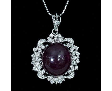 A ruby and diamond pendant, the large central cabochon ruby to an openwork white metal frame set with diamonds and on a fine 