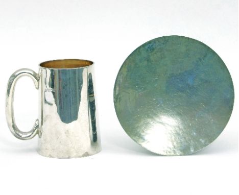 A silver mug, London 1907, with plain C scroll handle, 12cm high and a paten, HJB, London 1939, with hammered finish, 16cm di