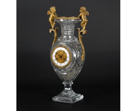 A 19th Century table clock mounted in a cut glass two handled vase, the ormolu bezel with floral surround and with white enam