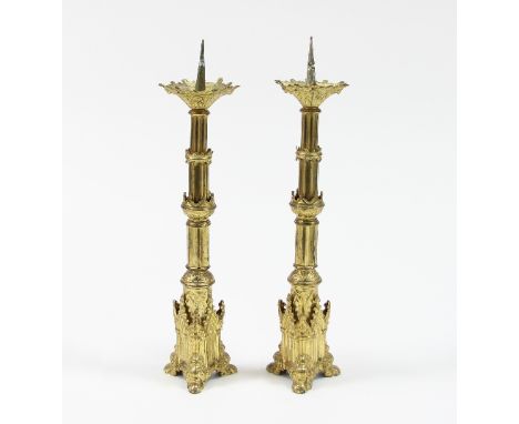 A pair of Pugin style gilt metal altar candlesticks, each with graduated stepped and reeded column, on tripod base with leaf 