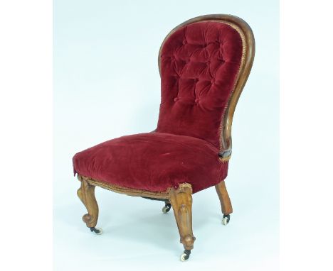 A Victorian walnut framed nursing chair with button back and stuffed seat in deep red velvet, on carved cabriole legs