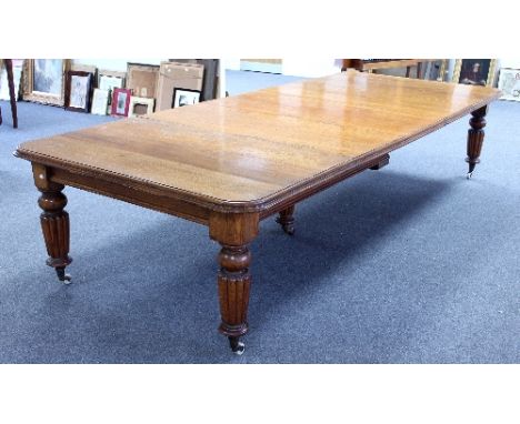 A Victorian oak dining table, the rounded rectangular top with moulded edge, on turned and reeded legs and central support wi