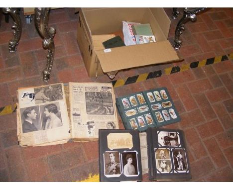 A medley of vintage postcards, cigarette cards and newspaper cuttings