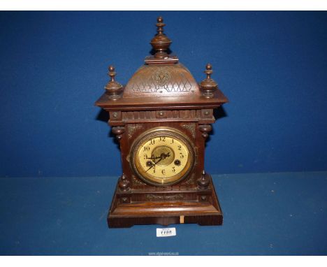 A wooden cased Mantle clock having Arabic numerals and finials to the top, a/f., with key and pendulum.