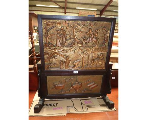 An ebonised hardwood chinoisiere Firescreen decorated with carved and gilded scenes of travellers and ap pair of figures with