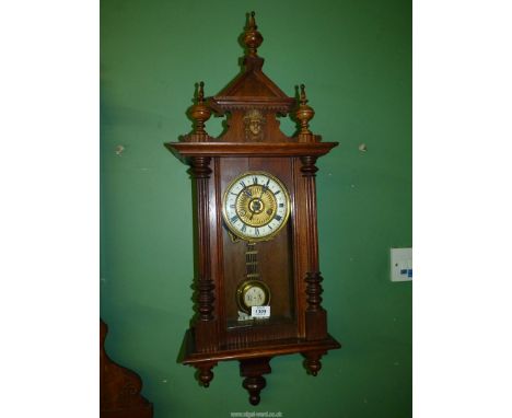 An Oak cased Vienna style wall Clock, the face with an ivory coloured chapter ring with Roman numerals, the case flanked with