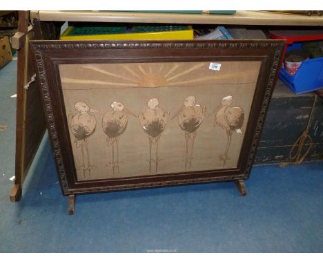 An embroidered fire screen with oak frame, the panel detailing five Storks paddling in the sea at sunset.
