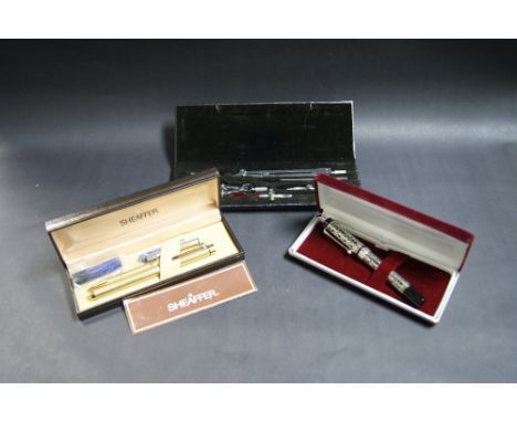 Gold-plated Sheaffer pen and pencil set, plus a white metal pen with a Sheaffer refill and a cased compass/geometry set. 