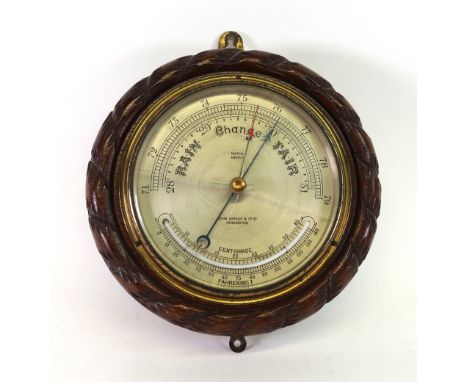 John Barker & Co Ltd Kensington: A Marine Aneroid barometer, with silvered dial, in a circular oak ropetwist carved case, 23c