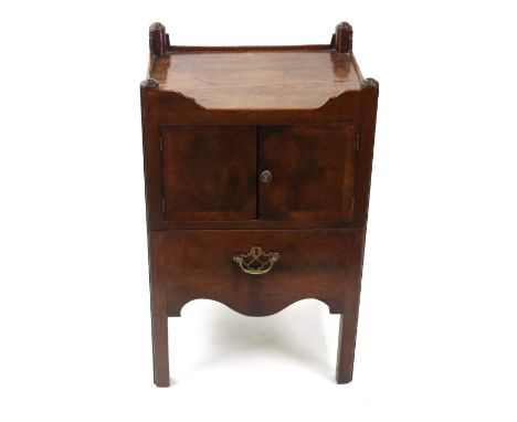 A George III mahogany night commode, the shaped tray top above a pair of crossbanded doors with a pull-out slide below, on mo