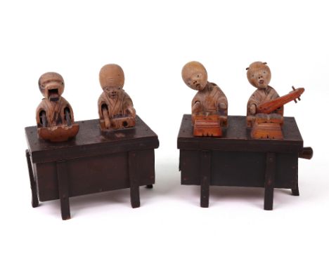 Two carved wooden Japanese Kobi toys, both with two figures on top of a box, one playing a musical instrument the other eatin