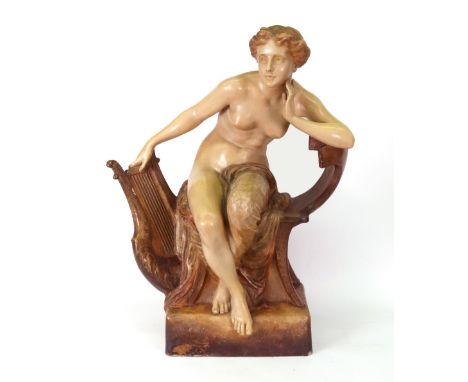 A Goldscheider figure of a young woman, partially draped, seated on a chair, one hand resting on a lyre, on a rectangular bas