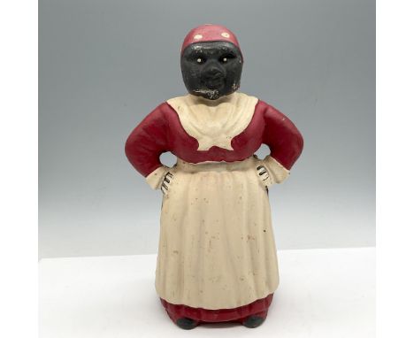 Standing with hands on hip and dressed in apron over her dress with a polka dot scarf on her head. Issued: 20th centuryDimens