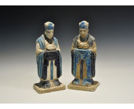 An undated archaistic pair of glazed ceramic figurines in Ming Dynasty, 1368-1644 AD style comprising: one standing on a rect
