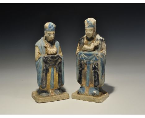 An undated archaistic pair of glazed ceramic figurines in Ming Dynasty, 1368-1644 AD style comprising: one standing on a rect