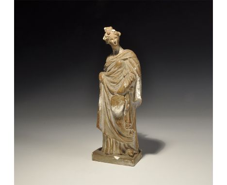 20th century AD. A hollow ceramic figurine of a standing robed female on a rectangular base. 511 grams, 24.5cm (9 3/4"). Prop