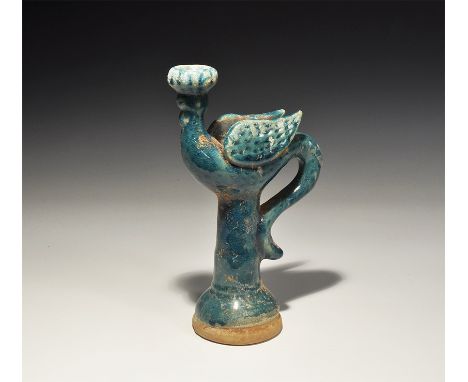An undated archaistic blue-glazed ceramic jug with flared base, tall neck, strap handle formed as a bird's tail, the body fla