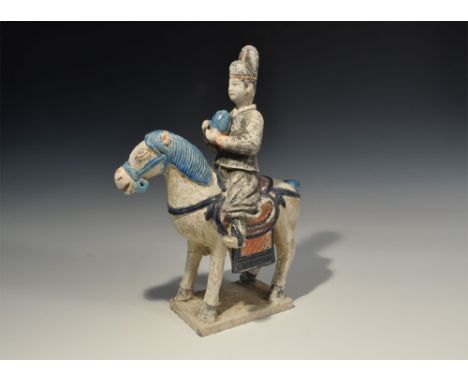 An undated archaistic part-glazed ceramic horse and rider figurine in Ming Dynasty, 1368-1644 AD style comprising: a standing