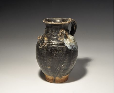 An undated archaistic barrel-shaped ceramic vessel with everted rim, short spout, two lateral loops, strap handle to the rear