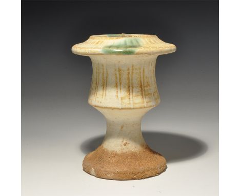 An undated archaistic white-glazed ceramic chalice with flared base, scooped body, broad flared rim, radiating ribs, green an