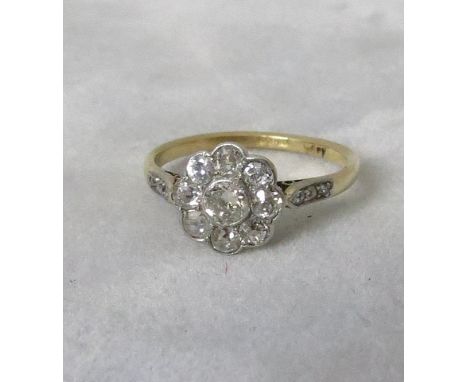 An early 20th century 18ct gold and platinum diamond daisy head ring with diamond set shoulders