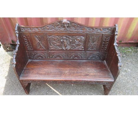 A Victorian carved oak bench, the back carved with styalized and scrolled leaf work, the centre with a figure playing a lyre,