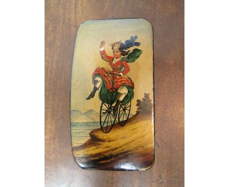 A 19th century papermache snuff box depicting a lady on a bicycle