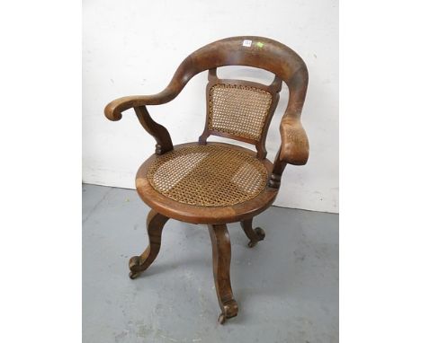 A late 19th century oak swivel desk chair having a cane seat