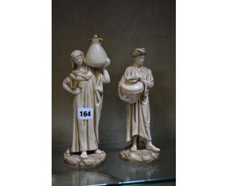 A pair of Royal Worcester figures of the Cairo Water Carriers, modelled by James Hadley in blush porcelain as a Middle Easter