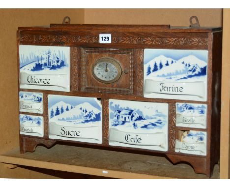 A early 20th Century Continental oak hanging kitchen cupboard, with clock, ceramic drawers, labelled 'sucre', 'cafe' etc, 52c