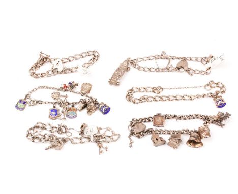 A group of six various silver and white metal charm bracelets, hung with various charms including churches, a skateboard, a c