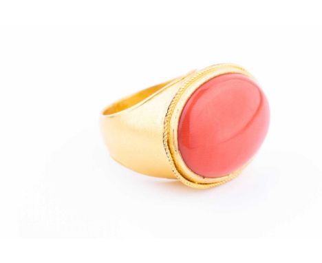 A yellow metal and cabochon coral ring, the coral measuring approx 22 mm x 17 mm, the ring stamped 900, size K.