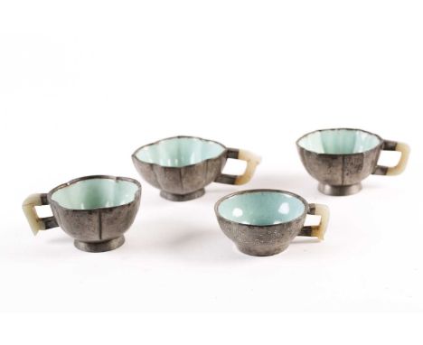 Four Chinese inscribed pewter, Yixing and jade tea cups, Qing, late 19th century, of varying shape, three with celadon glaze 
