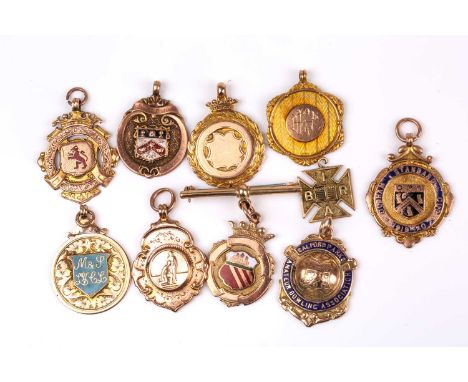 A group of ten various early 20th century 9ct rose and yellow gold sporting award medallion pendants, some with enamel decora