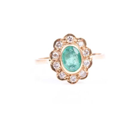 An 18ct yellow gold, diamond, and emerald cluster ring, set with a mixed oval-cut emerald, approximately 6 x 5 mm, within a s