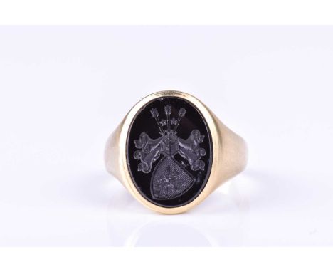A gentleman's signet ring, set with an intaglio egraved crest to oval onyx plaque, within a tapering yellow metal band. size 
