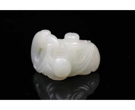 A Chinese celadon jade crane, 18th century, a fruiting peach branch in its beak, the stone a good uniform colour throughout, 