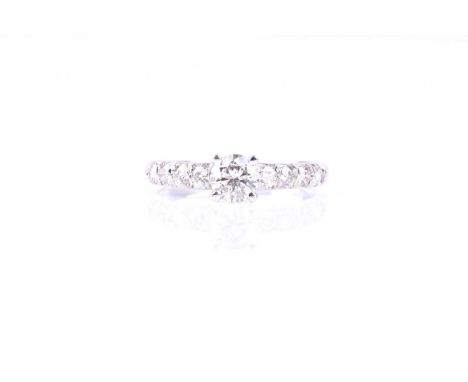 A single stone diamond ring, the round brilliant cut diamond in four claw mount, above slightly graduated four stone brillian