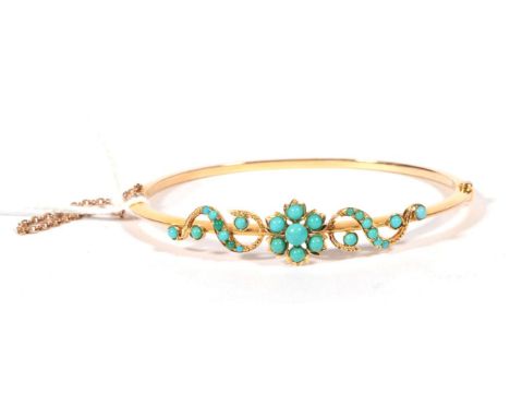 ~ An early 20th century turquoise bangle, a floral cluster of turquoise between turquoise set scrolls, on a hinged plain bang