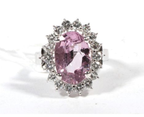 A pink spinel and diamond cluster ring, an oval cut pink spinel within a border of round brilliant cut diamonds, to forked sh