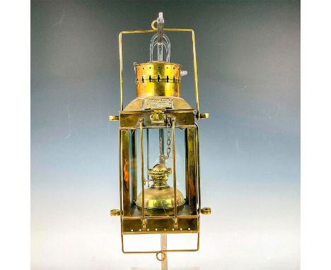 A hanging ship lantern in a brass frame with four glass sides. Plaque reads 'Cargo Light No. 3954 Great Britain 1939' embosse