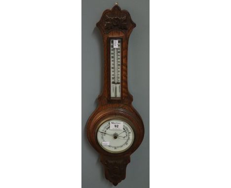 Small early 20th Century oak wheel barometer with thermometer and carved foliate decoration.(B.P. 24% incl. VAT)