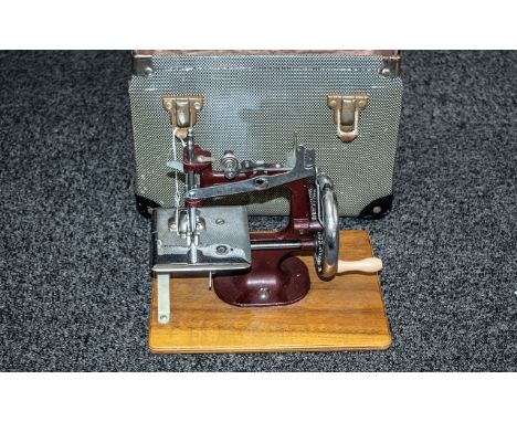 Mid 20th Century Child's Miniature Sewing Machine, in chrome with burgundy enamel frame. in carry case.  Height 7", appears u