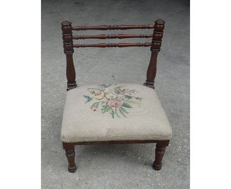 A Child's Victorian mahogany frame low Chair with spindle turned back, tapestry upholstered seat on short turned supports.  