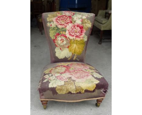 A Victorian low Chair with fan shaped back, upholstered in floral tapestry and on short turned supports, the casters inscribe