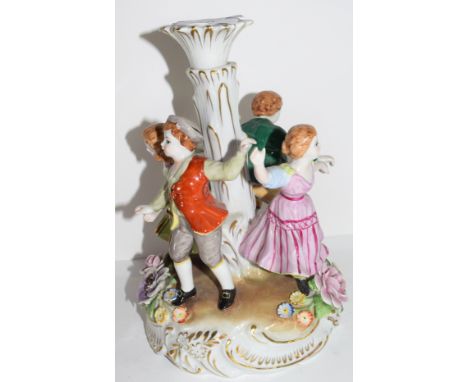 Continental porcelain candlestick in Meissen style decorated with children dancing around a central column, 26cm high